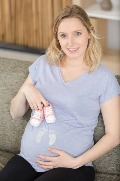 Lycklig Gravid Kvinna Håller Små Skor Vidrör Magen — Stockfoto