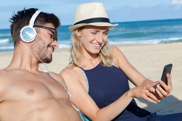 美丽的年轻夫妇在海滩上使用移动电话 — 图库照片