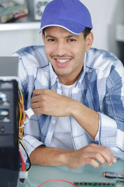 坐在计算机旁边的快乐的微笑修理工 — 图库照片
