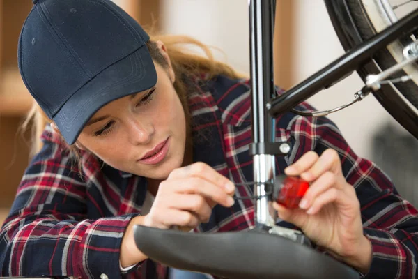 自転車修理工場で働く若い女性が — ストック写真