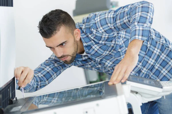 Man Leaning Open Photocopier Maintenance Repairs Using Screwdriver — Stock Photo, Image