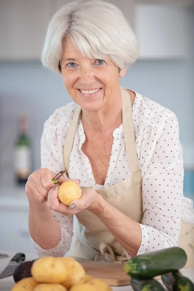 Reife Frau Schält Kartoffeln Für Das Abendessen — Stockfoto