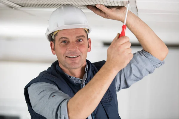 天井空気フィルターを取り除く幸せな男性労働者 — ストック写真