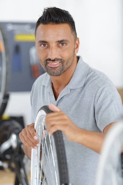 40多岁的男人在商店里修理自行车轮 — 图库照片