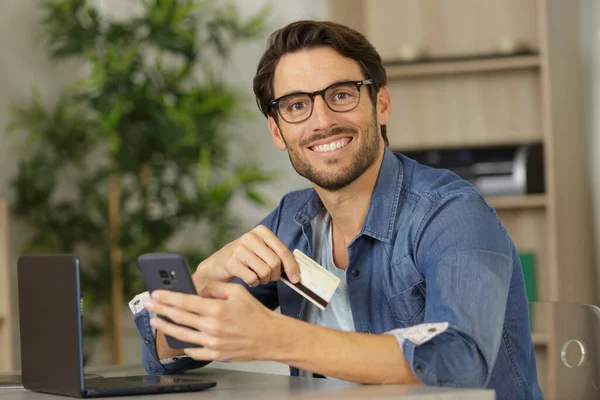 Sorrindo Homem Sentado Escritório Paga Com Cartão Crédito — Fotografia de Stock
