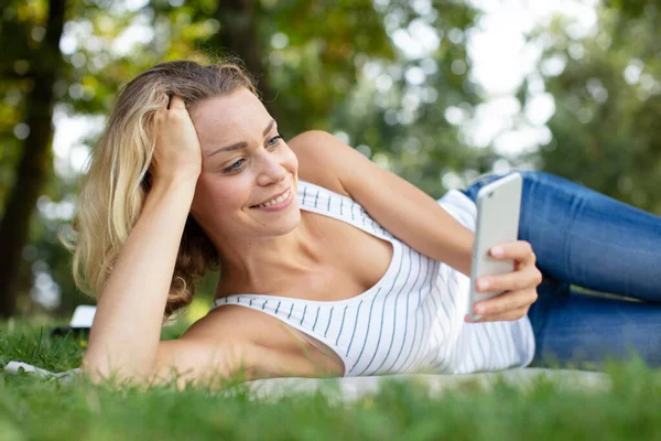 Mulher Usando Telefone Inteligente Descansando Grama — Fotografia de Stock