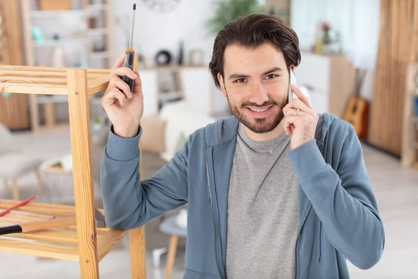 Man Assembling Furniture Home Holds Screwdriver Telephone — Stock Photo, Image