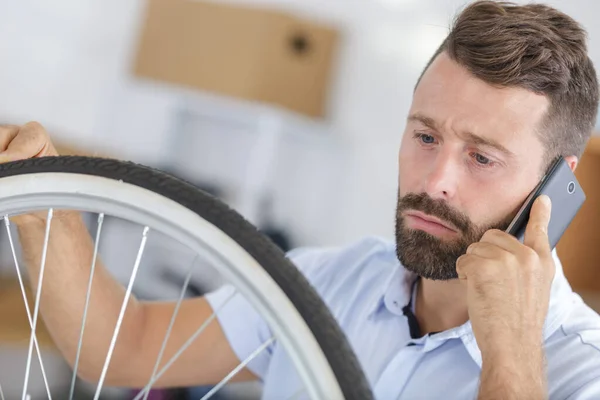 Mężczyzna Telefonie Naprawianie Koła Rowerowego — Zdjęcie stockowe