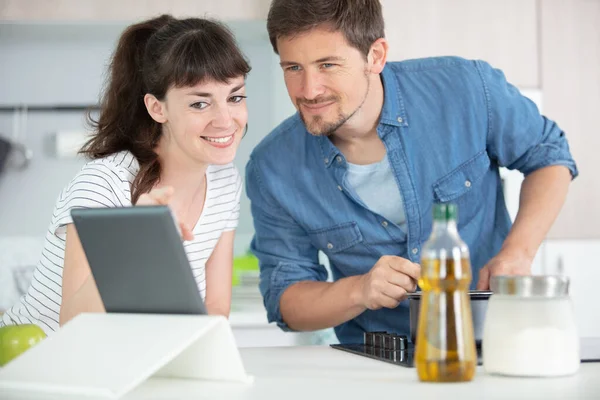 Casal Está Usando Tablet Digital Sorrindo Enquanto Cozinha — Fotografia de Stock