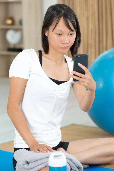 Mujer Estera Yoga Mirando Teléfono Inteligente —  Fotos de Stock