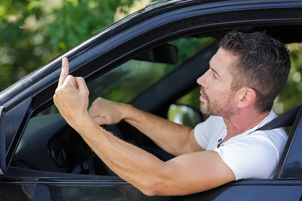 Yakışıklı Bir Adam Araba Kullanıyor Orta Parmağını Gösteriyor — Stok fotoğraf