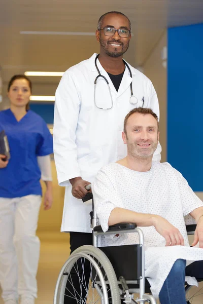 Erkek Doktor Hastayı Tekerlekli Sandalyeye Itiyor — Stok fotoğraf
