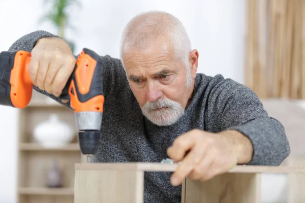 Alter Mann Bohrt Holzmöbel Hause — Stockfoto