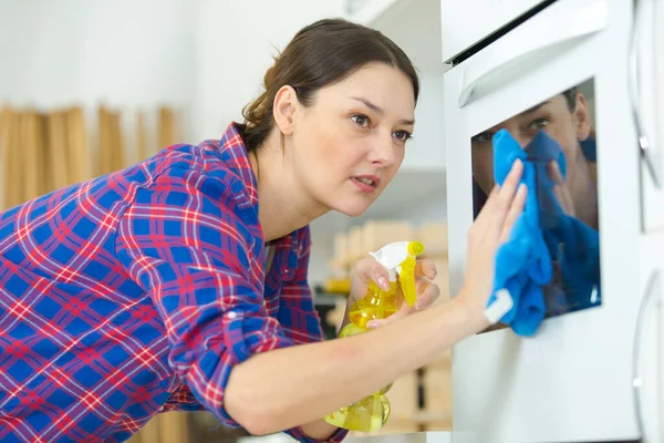 ラグでオーブンを掃除する女性 — ストック写真