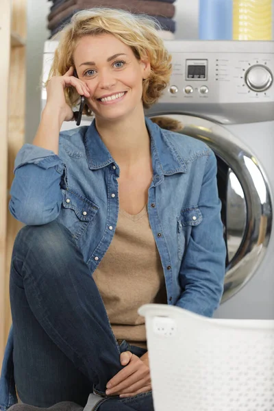 Mulher Falando Telefone Inclinado Máquina Lavar Roupa — Fotografia de Stock