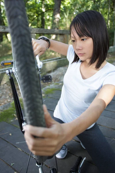 公園で自転車を修理する女性は — ストック写真