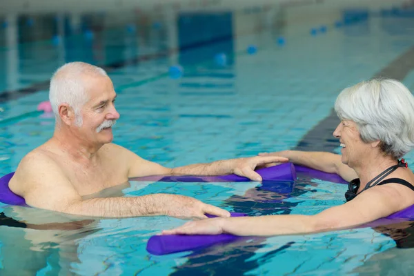 老夫婦はプールで運動運動をしています — ストック写真