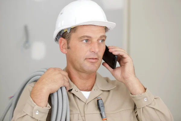 成熟的男性建筑工人 携带电缆和使用电话 — 图库照片