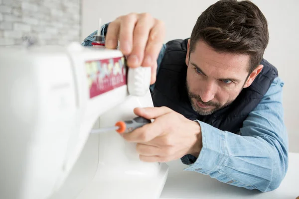 man repairing a sewing machine