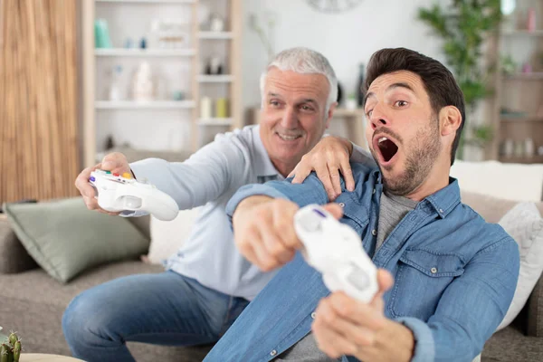 成熟した息子と高齢者の父親はビデオゲームを楽しんでいます — ストック写真