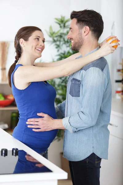 怀孕的夫妇要在厨房接吻了 — 图库照片