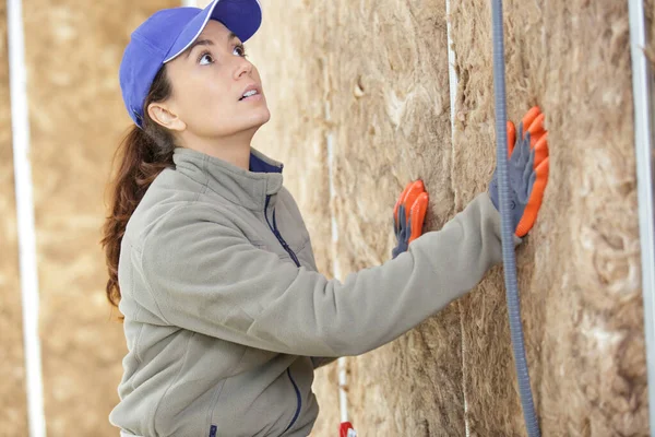 女性労働者が壁に断熱材を詰め込み — ストック写真