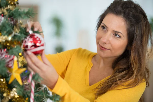 圣诞节期间 快乐的女人在家里用装饰品装饰圣诞树 — 图库照片