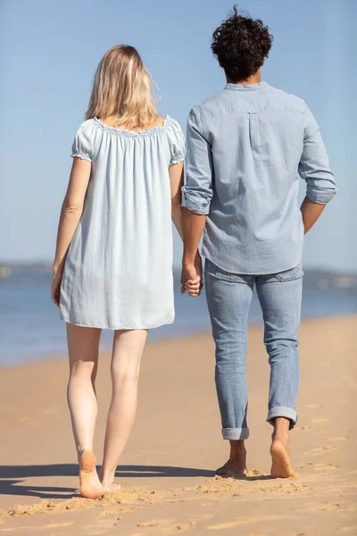 幸せな若いカップルが立ってビーチで手を取り合って — ストック写真