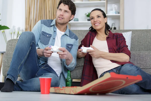 夫妻在家里玩电子游戏的同时吃着美味的披萨 — 图库照片