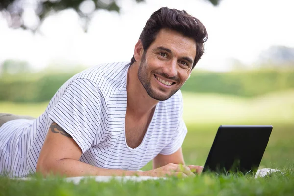 Mann Liegt Auf Gras Und Arbeitet Seinem Laptop — Stockfoto