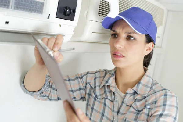 幸せな女性労働者はエアコンを修理しています — ストック写真