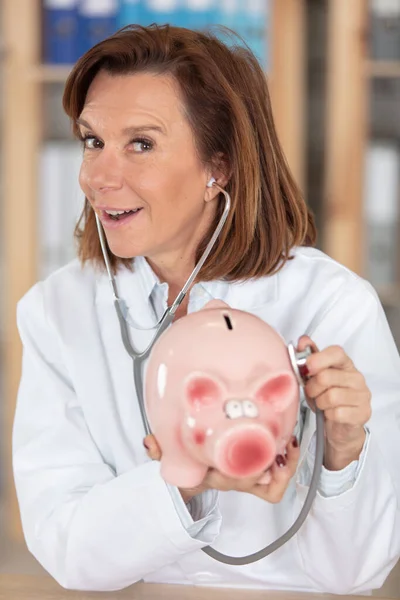 Verspielter Arzt Hält Stethoskop Sparschwein — Stockfoto