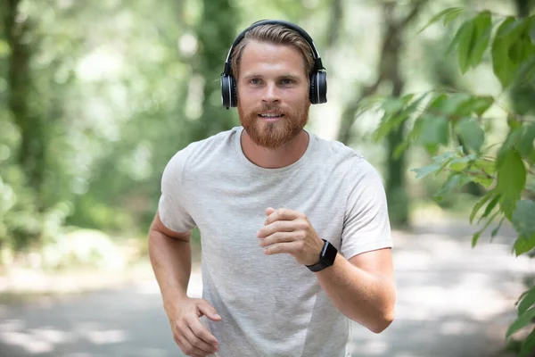 Νεαρός Άνδρας Δρομέας Χρησιμοποιώντας Ακουστικά Τρέχει Στη Φύση — Φωτογραφία Αρχείου