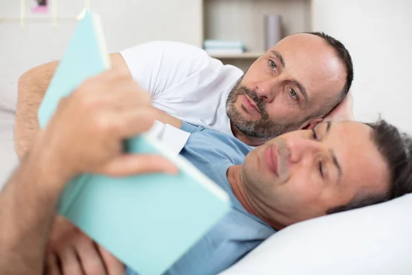 ベッドの上の幸せなゲイのカップル読書 — ストック写真