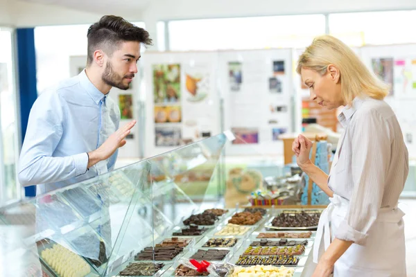 年轻人在糖果店柜台选高档巧克力 — 图库照片