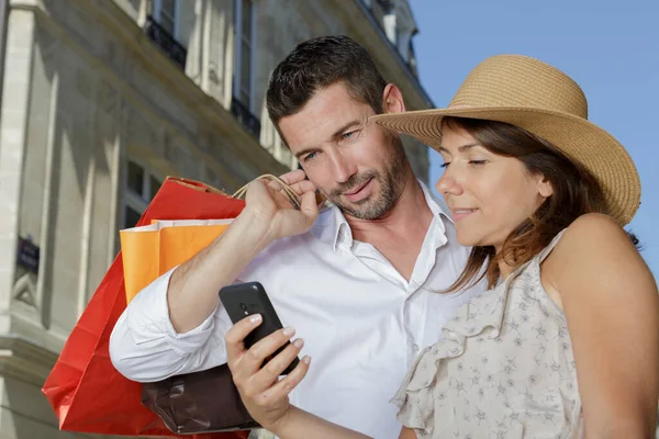 Para Patrząc Telefon Komórkowy Podczas Zakupów — Zdjęcie stockowe