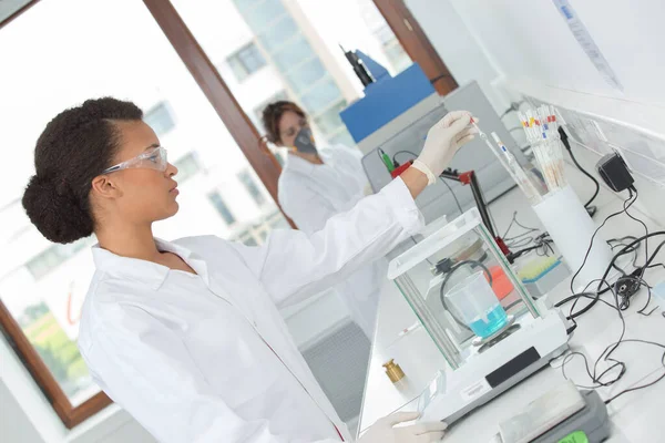 Két Női Asszisztens Méri Folyadékot Kémiai Laborban — Stock Fotó