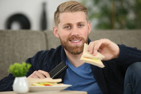 Άνθρωπος Χαλαρώνοντας Ενώ Τρώει Ένα Σάντουιτς Στο Σπίτι — Φωτογραφία Αρχείου