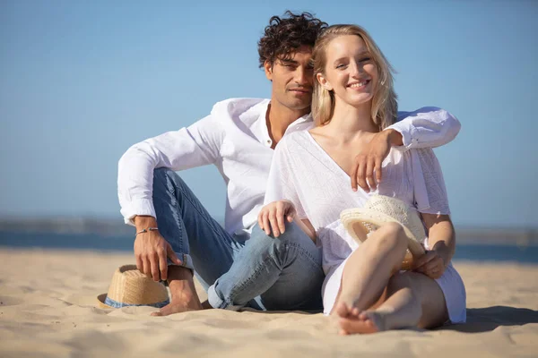 夏のビーチに座っている若いカップルは — ストック写真