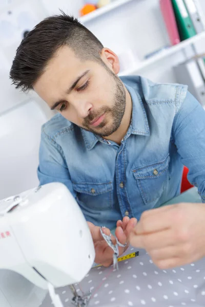 年轻快乐的男裁缝在缝纫机上工作 — 图库照片