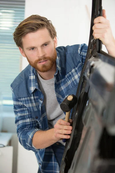 ゴム製のマレットで車のドアを修理する男 — ストック写真