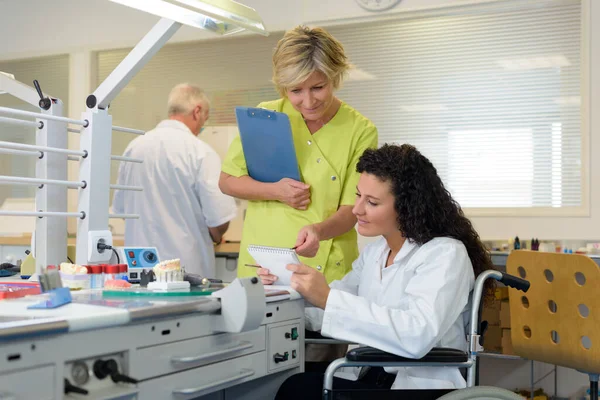 manager assisting wheelchair worker in a lab