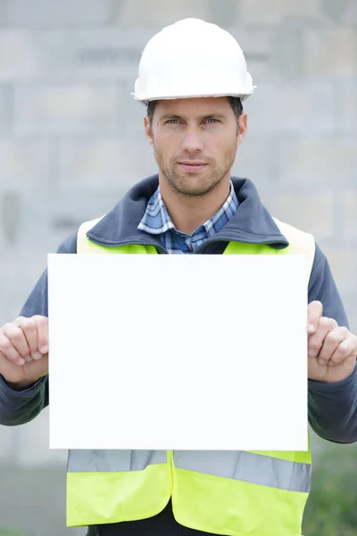 Χαμογελαστός Εργάτης Που Δείχνει Μια Λευκή Πινακίδα — Φωτογραφία Αρχείου