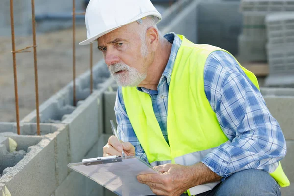 Senior Werknemer Een Beschermende Helm Controleren Klembord Buiten — Stockfoto