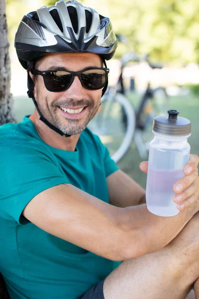 中年男子骑自行车的人休息一下 拿着水瓶 — 图库照片