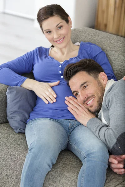 男人把耳朵靠在怀孕的妻子的肚子上 — 图库照片