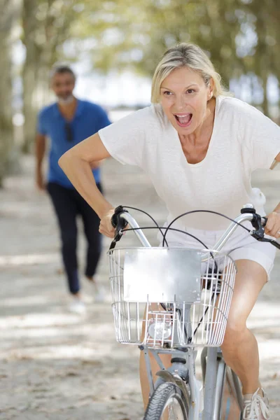 快乐成熟的女人在夏季公园骑自行车 — 图库照片
