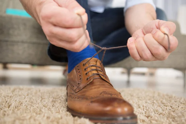 man tying the laces on his brogue shoes