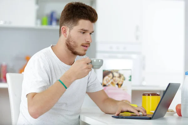 在家里工作的男人 在厨房桌上拿着笔记本电脑 — 图库照片
