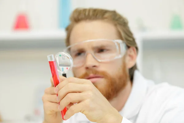 带放大镜在实验室工作的化学人员 — 图库照片